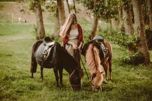 a woman standing next to two horses in a field at Przystań na Zagórzu - Apartamenty nad jeziorem in Drezdenko +113 photos