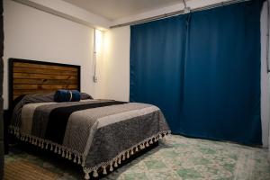 een slaapkamer met een bed met een blauw gordijn bij Casa Iztac in Zacatlán