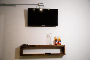 einen Flachbild-TV an einer Wand mit Flaschen auf einem Regal in der Unterkunft Casa Iztac in Zacatlán