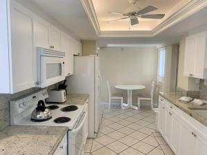 a kitchen with white cabinets and a white refrigerator at Island House Beach Resort 3N in Siesta Key