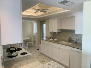 a kitchen with white cabinets and a ceiling fan at Island House Beach Resort 3N in Siesta Key