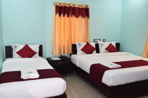 two beds in a hotel room with red curtains at Grand Pacific in Puducherry