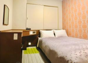 1 dormitorio con 1 cama, escritorio y armario en Urban Place Inn Kokura, en Kitakyushu