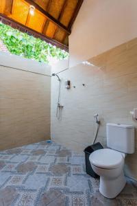 a bathroom with a toilet on a tile floor at Camar Cottage & Hostel in Nusa Penida