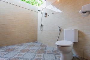 a bathroom with a toilet and a shower with a window at Camar Cottage & Hostel in Nusa Penida