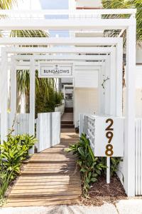a white entrance to a building with a wooden boardwalk at The Bungalows at Bondi in Sydney