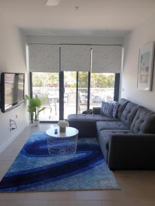 sala de estar con sofá y alfombra azul en Luxury Beach Front Appartment en Rosebud