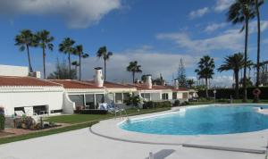 a swimming pool in front of a house with palm trees at Villa in Duna Golf in Playa del Ingles