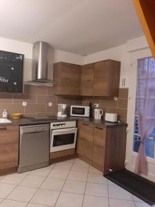 a kitchen with stainless steel appliances and wooden cabinets at La petite maison in Bracquemont