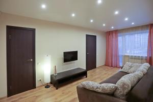 uma sala de estar com um sofá e uma televisão de ecrã plano em Ural Apartment em Chelyabinsk
