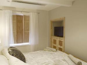 a bedroom with a bed and a window and a television at Upside Down Cottage in Richmond