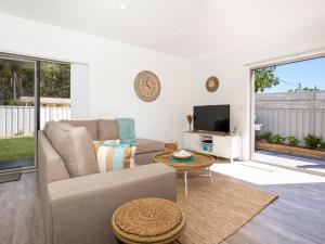 a living room with a couch and a tv at Salty Shores Jervis Bay I 3 Mins to Beach in Callala Beach