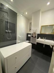 La salle de bains est pourvue d'une baignoire, d'un lavabo et d'une douche. dans l'établissement Apartment Elli, à Augsbourg