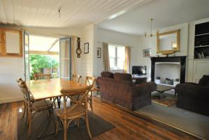 ein Wohnzimmer mit einem Tisch, Stühlen und einem Kamin in der Unterkunft Cooma Cottage in Cooma