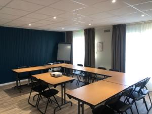 une salle de classe avec des tables, des chaises et un écran dans l'établissement Hôtel Inn Design Resto Novo Nantes Sainte Luce, à Sainte-Luce-sur-Loire