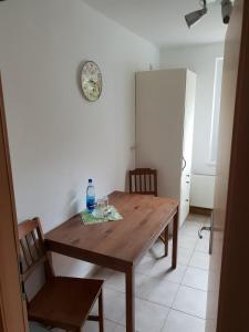 a wooden table with two chairs and a clock on the wall at SchlafSchön Apartment- Monteurunterkunft Gerichshain in Gerichshain