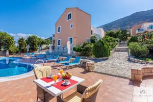 een patio met een tafel en stoelen en een zwembad bij Pilot's Villas Luxury Suites in Chersonissos