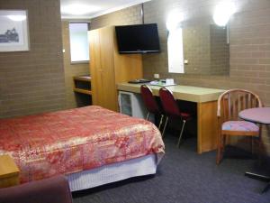 ein Hotelzimmer mit einem Bett, einem Schreibtisch und einem Tisch in der Unterkunft Mildura Motor Inn in Mildura