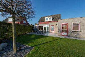 ein Haus mit einem grünen Garten mit einem Baum in der Unterkunft Antibes 198 - Kustpark Village Scaldia in Hoofdplaat