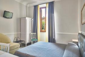 a bedroom with a bed, chair and a window at Albergo Chiusarelli in Siena