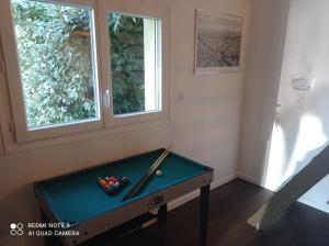 um quarto com uma mesa de bilhar e duas janelas em Studio à la campagne aux portes de Nantes em Saint-Mars-du-Désert