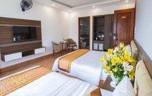 ein Hotelzimmer mit 2 Betten und einer Vase aus Blumen in der Unterkunft Tan Truong Son Legacy Hotel in Sầm Sơn