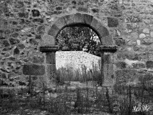 Casa Melania في Cepeda: صورة من اللون الأسود والأبيض لجدار حجري مع نافذة