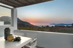 a white dining room with a view of the ocean at White Tinos Luxury Suites in Stení