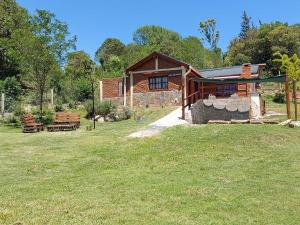 una cabaña de madera con bancos frente a un patio en Terra Vista en Huerta Grande