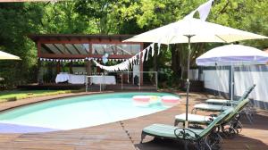 a swimming pool with two chairs and an umbrella at The Oak Potch Guesthouse in Potchefstroom