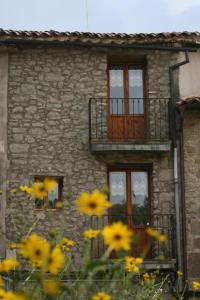 un edificio de piedra con balcón y flores amarillas en Cal Ferrer Nou en Alpens