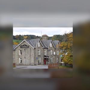 Um velho edifício de pedra com um sinal. em The Llanelwedd Arms Hotel em Builth Wells