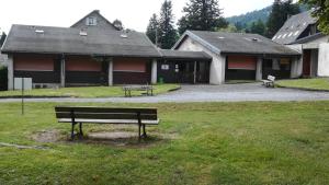 un banc dans l'herbe devant un bâtiment dans l'établissement Cocooning Auvergnat, à La Bourboule