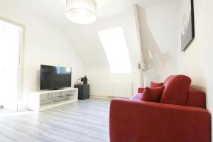 Domaine Providence في Lassay-sur-Croisne: غرفة معيشة مع أريكة حمراء وتلفزيون