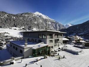 a building in the snow with mountains in the background at Apart Alpenjuwel Sölden in Sölden