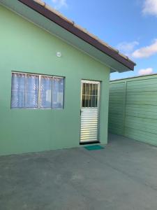a green and white house with a garage at Casa, 1 quadra da praia. in Ilha Comprida