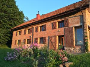 una vieja casa de ladrillo con un jardín delante de ella en Spichlerz Nad Jeziorem Dadaj Mazury, en Biskupiec