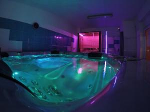 El baño incluye una gran bañera verde con iluminación púrpura. en Vila Cristal, en Băile Felix