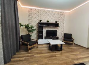 een woonkamer met 2 stoelen, een tafel en een tv bij Люкс апартаменти двокімнатні в центрі міста на Ерусалимці поруч з фонтаном Рошен in Vinnytsya