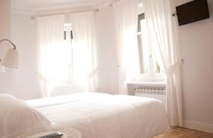 a white bedroom with a bed and a window at Hostal Boreal Mistral in Burgos