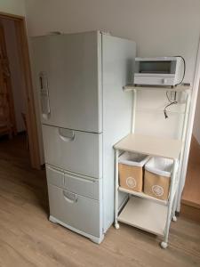 einen weißen Kühlschrank neben einem Regal mit einer Mikrowelle in der Unterkunft ゲストハウス・東海　長良川 in Gifu