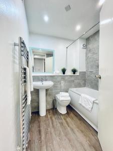 a bathroom with a tub and a sink and a toilet at Bijou Merchant City Apartment with Parking (Albion 1) in Glasgow