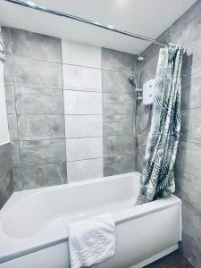 a bathroom with a white tub and a shower at Bijou Merchant City Apartment with Parking (Albion 1) in Glasgow