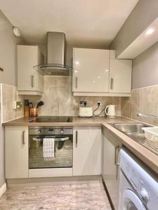 a kitchen with white cabinets and a stove top oven at Bijou Merchant City Apartment with Parking (Albion 1) in Glasgow