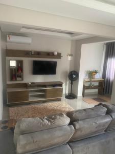 een woonkamer met een bank en een flatscreen-tv bij Casa ao lado do parque Beto carreiro da de ir a pé para o parque João carlos casas in Penha