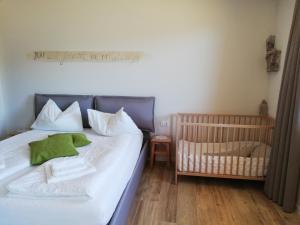 a bedroom with a crib and a bed with white sheets at Casa Lassù in Carano