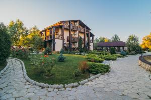 uma casa grande com um jardim em frente em Котедж-парк Славна em Okhtyrka