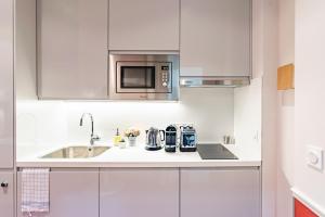 a white kitchen with a sink and a microwave at Citihome Paris in Paris