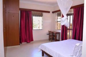 坎帕拉A wonderful apartment in the city of kampala的卧室配有白色的床和红色窗帘 更多16张照片