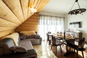 a living room with a couch and a dining room table at Szymoszkowa Residence Ski & basen sauny jacuzzi - apartament Szara Owca in Kościelisko